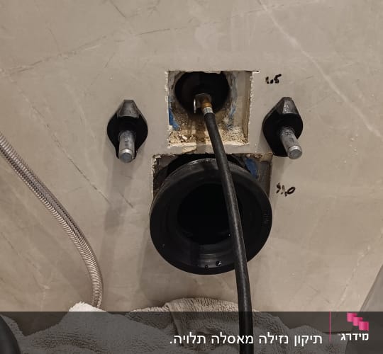 חיבור צינור בקיר עם מגבת על הרצפה